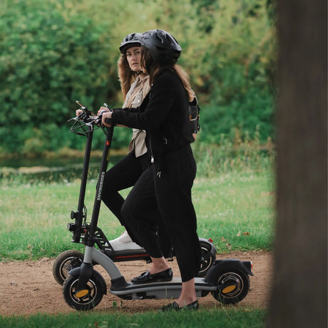 Two riders wearing helmets on an electric scooter