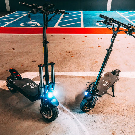 Two electric scooters with lights illuminated at night
